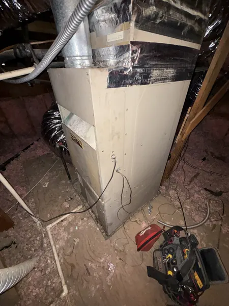 Attic furnace with a technician's tool bag beside it during a blower motor overheating diagnosis in Reedley, CA