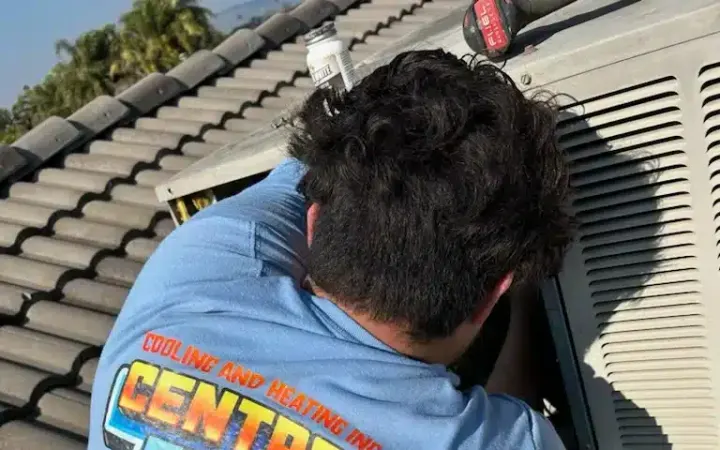 Central Elite technician repairing a rooftop air conditioner in Fresno CA
