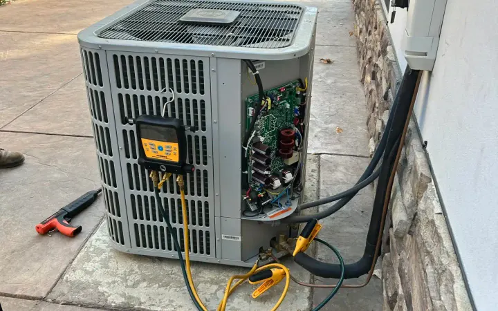 Central Elite technician commissioning a new outdoor heat pump unit with digital gauges